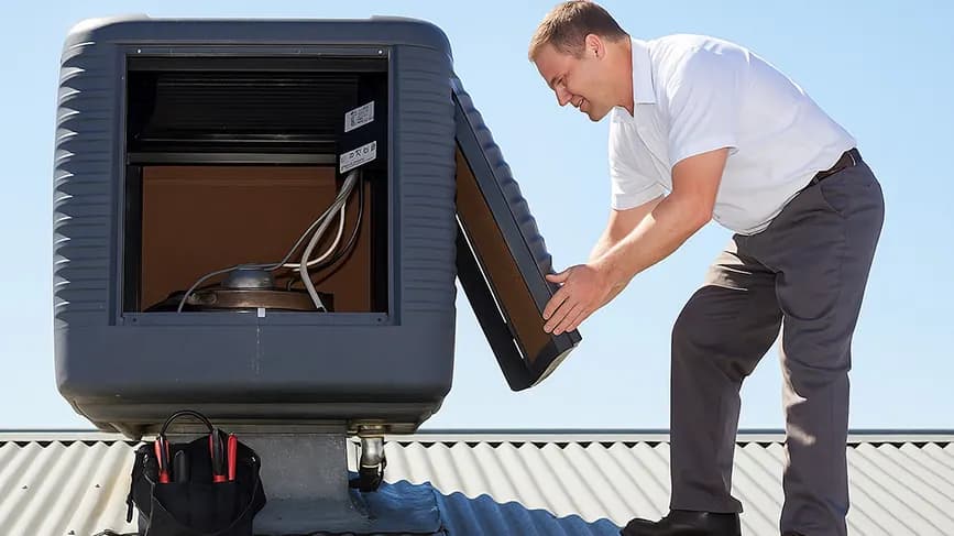 Technician opening an evaporative cooler on a Melbourne roof